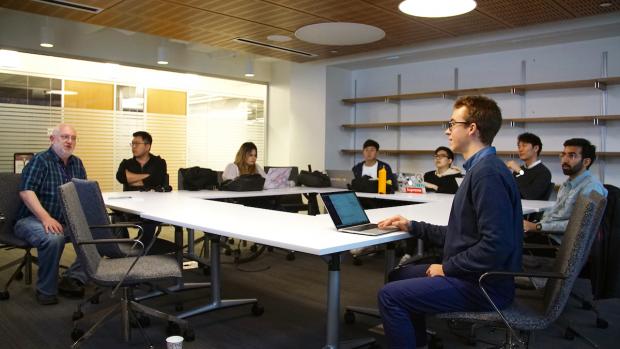 Professor Callahan seated at table with students.