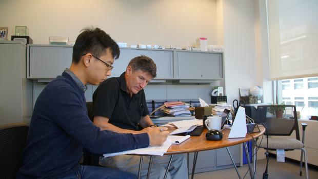 FRE student studying with Prof. Carr at desk