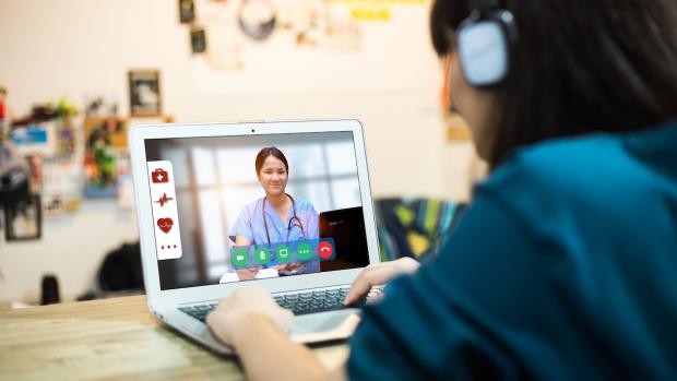 female with laptop during online medical consultation with her doctor via video call