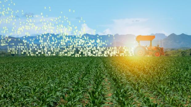 Tractor driving across green field with data coming out of the back