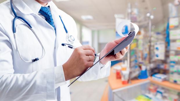 doctor in white lab coat writing on a clipboard