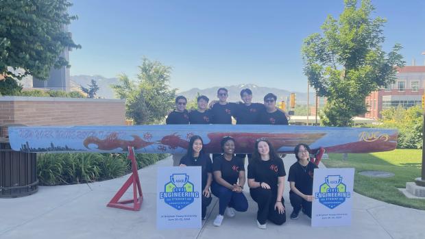 the team posing with their canoe with mountain range in background