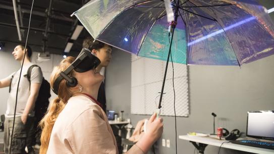 student wearing VR headset looking up at umbrella