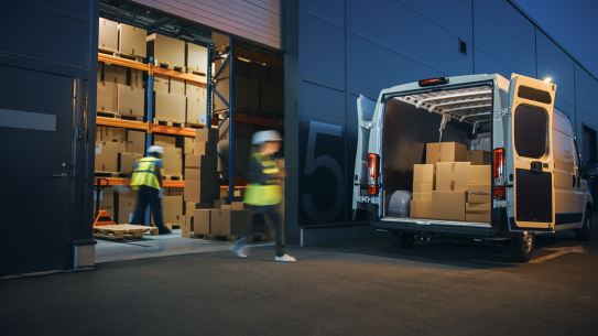 Two workers filling up a delivery truck with packagages