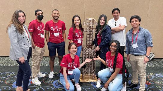  NYU Tandon Seismic Design Team members posing infront of a human size wood stick construction