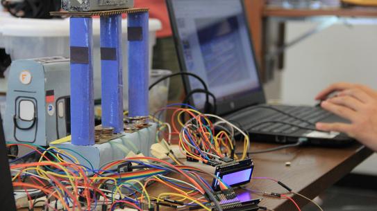 close up of circuits with hands typing on keyboard in background