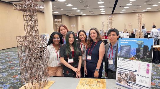 Team gathered and faculty advisor around presentation table, structure, and poster at 2023 presentation day