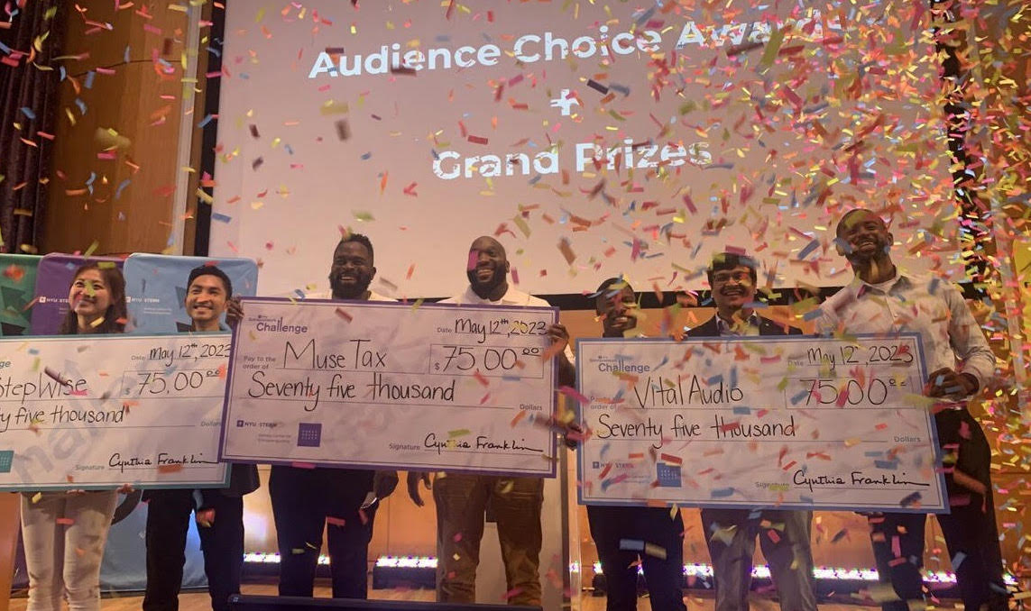 student teams holding oversized checks and confetti falling from above